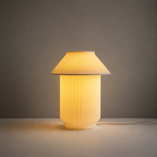 A pleated table lamp with a warm yellow glow, featuring a conical shade and a ribbed cylindrical base, set against a neutral gray background.