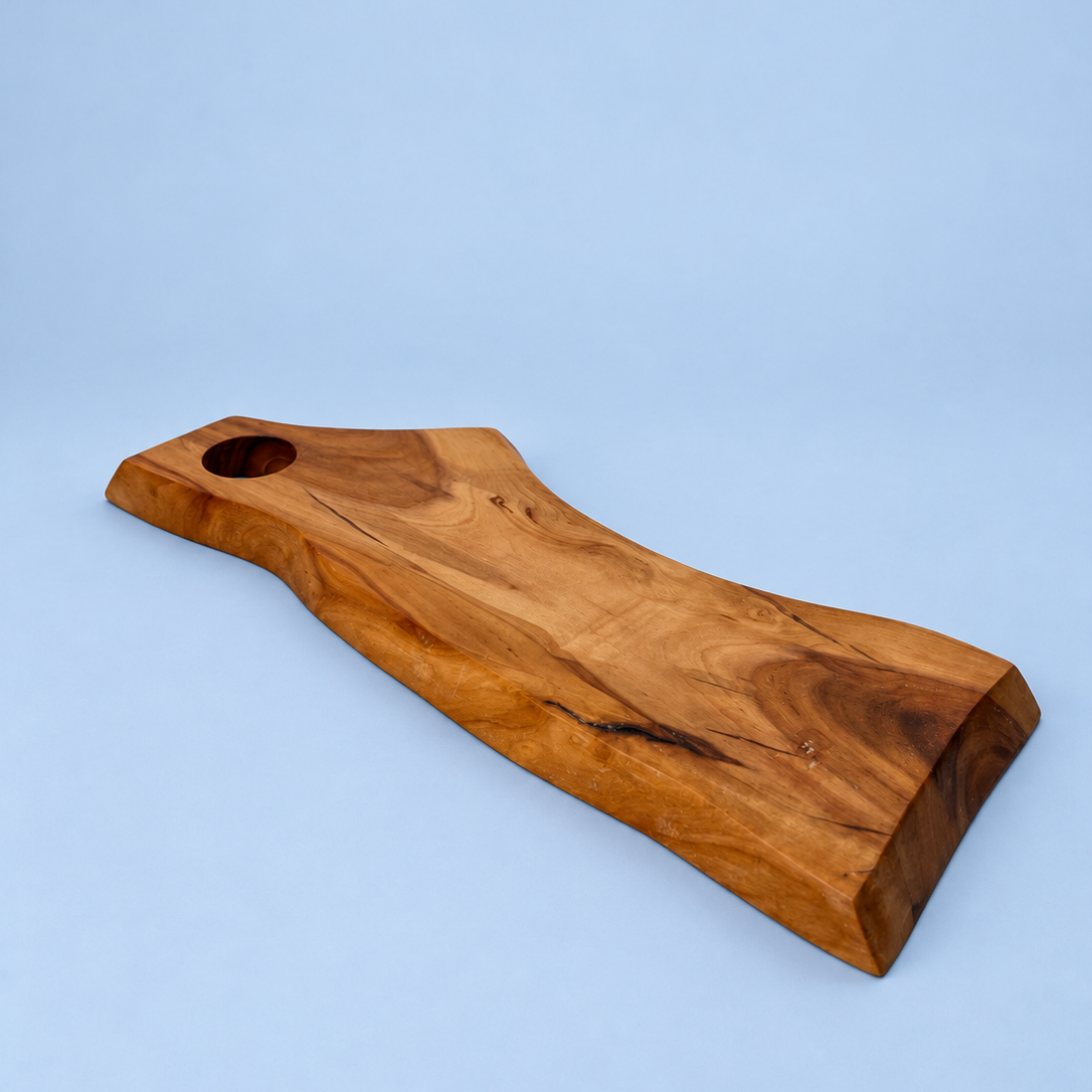 A live-edge wooden serving board with a natural grain pattern and a circular cutout in one corner, displayed on a light blue background.